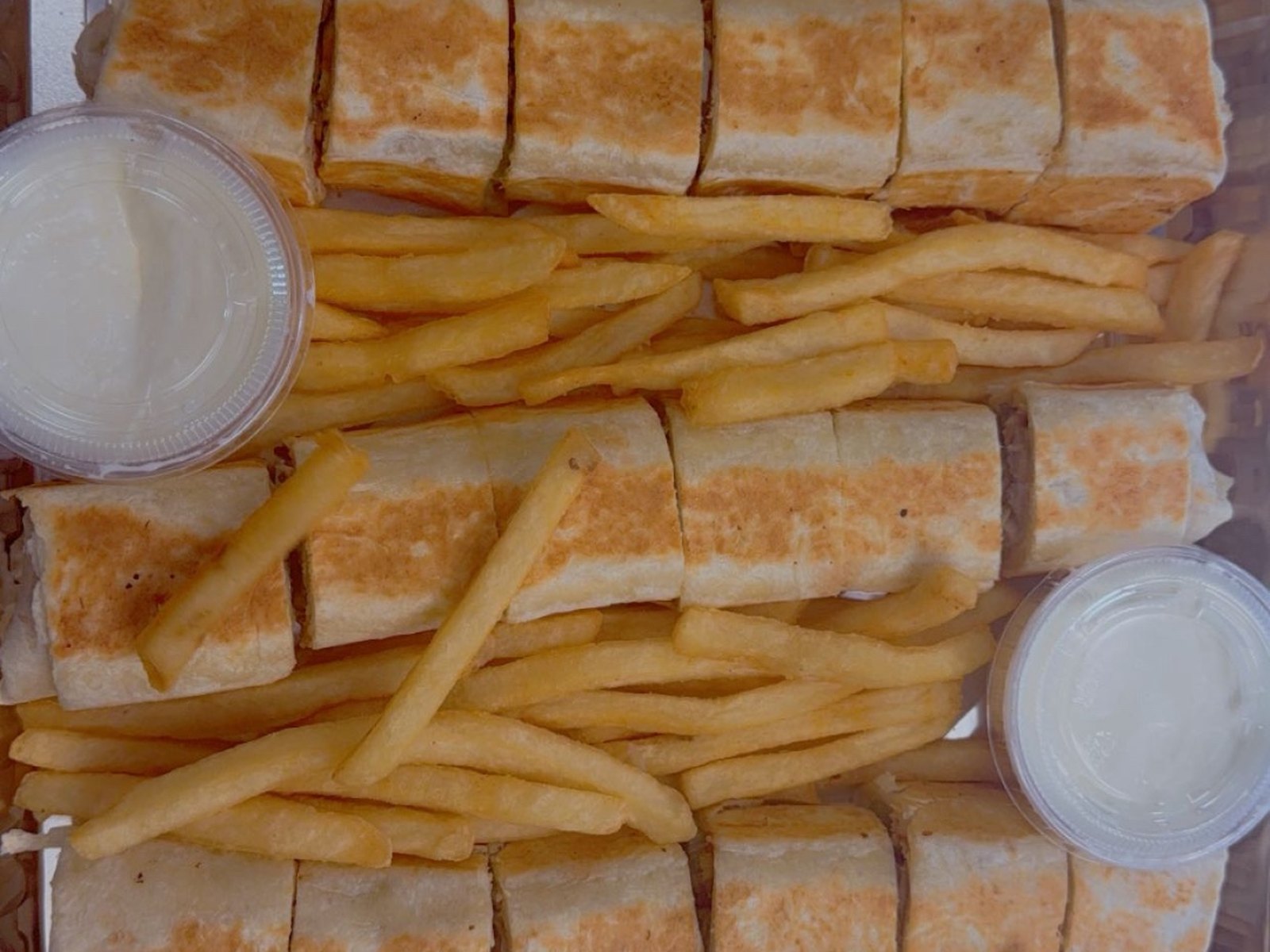 Catering tray of shawarma rolls with fries and garlic sauce