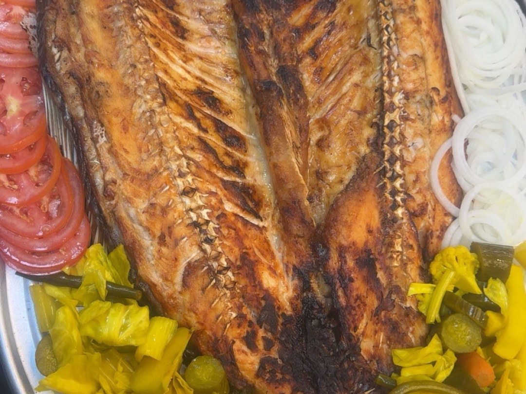 Large grilled fish platter with pickles and onion
