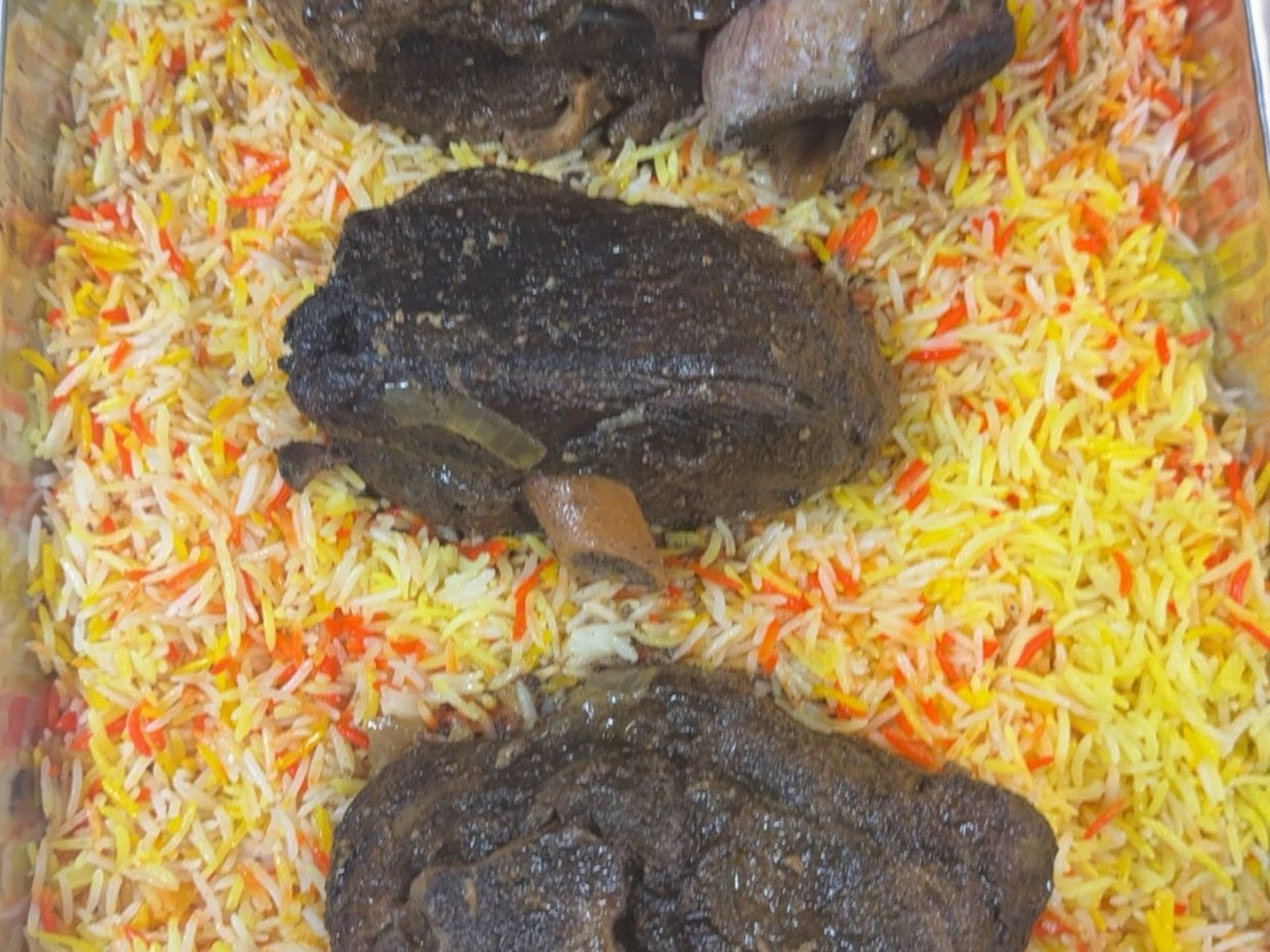 Lamb quzi pieces over colorful rice catering tray